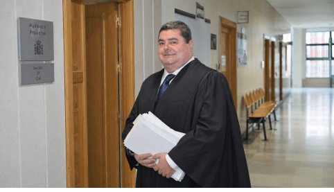 Abogado penalista con toga en pasillos del Tribunal de Instancia preparando la defensa en un caso de denuncia falsa y simulación de delito.