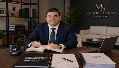 Abogado de familia en Sevilla revisando un expediente sobre pensión de alimentos de hijo mayor de edad en el despacho Madrid Salinas Abogados.