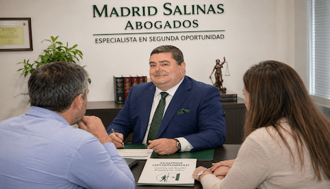 Abogado explicando a dos clientes cómo cancelar deudas mediante la Ley de la Segunda Oportunidad en Madrid Salinas Abogados